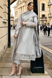 Woman wearing grey embroidered raw silk suit with diagonal color-blocked border under stone archway