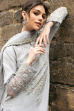 Woman wearing grey embroidered raw silk suit with diagonal color-blocked border under stone archway