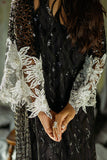 Close-up of clasped hands and embroidered sleeve detail on a Black Net suit
