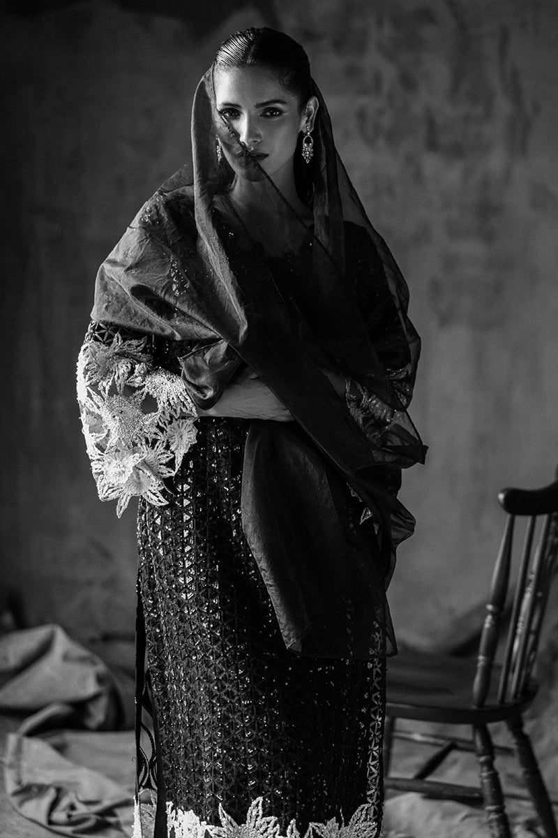 Black-and-white close-up in a Black Net suit, arms crossed beneath an organza veil