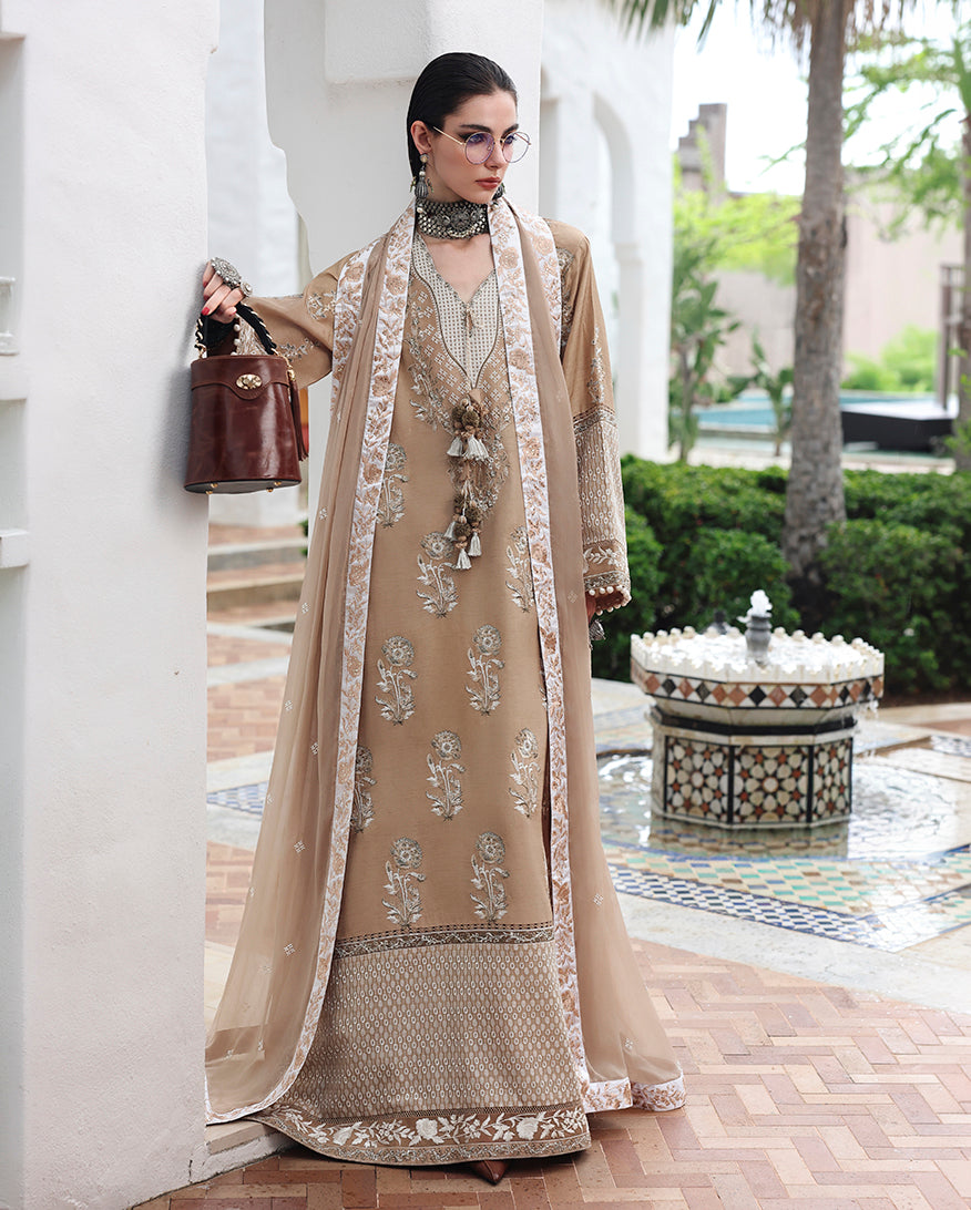 Woman wearing beige raw silk dress with hand embellished neckline tassels and dupatta draped over the arm