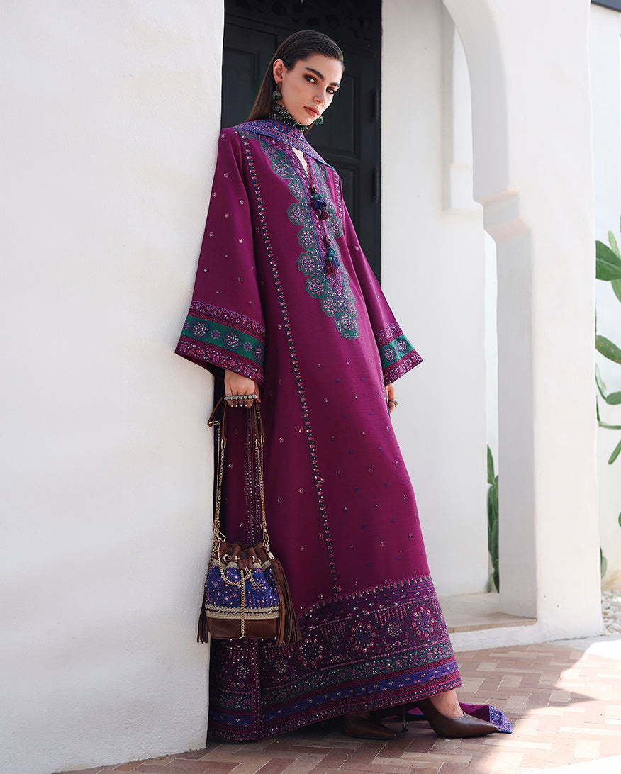 Side view of magenta raw silk suit with sequinned sleeve border, leaning against archway