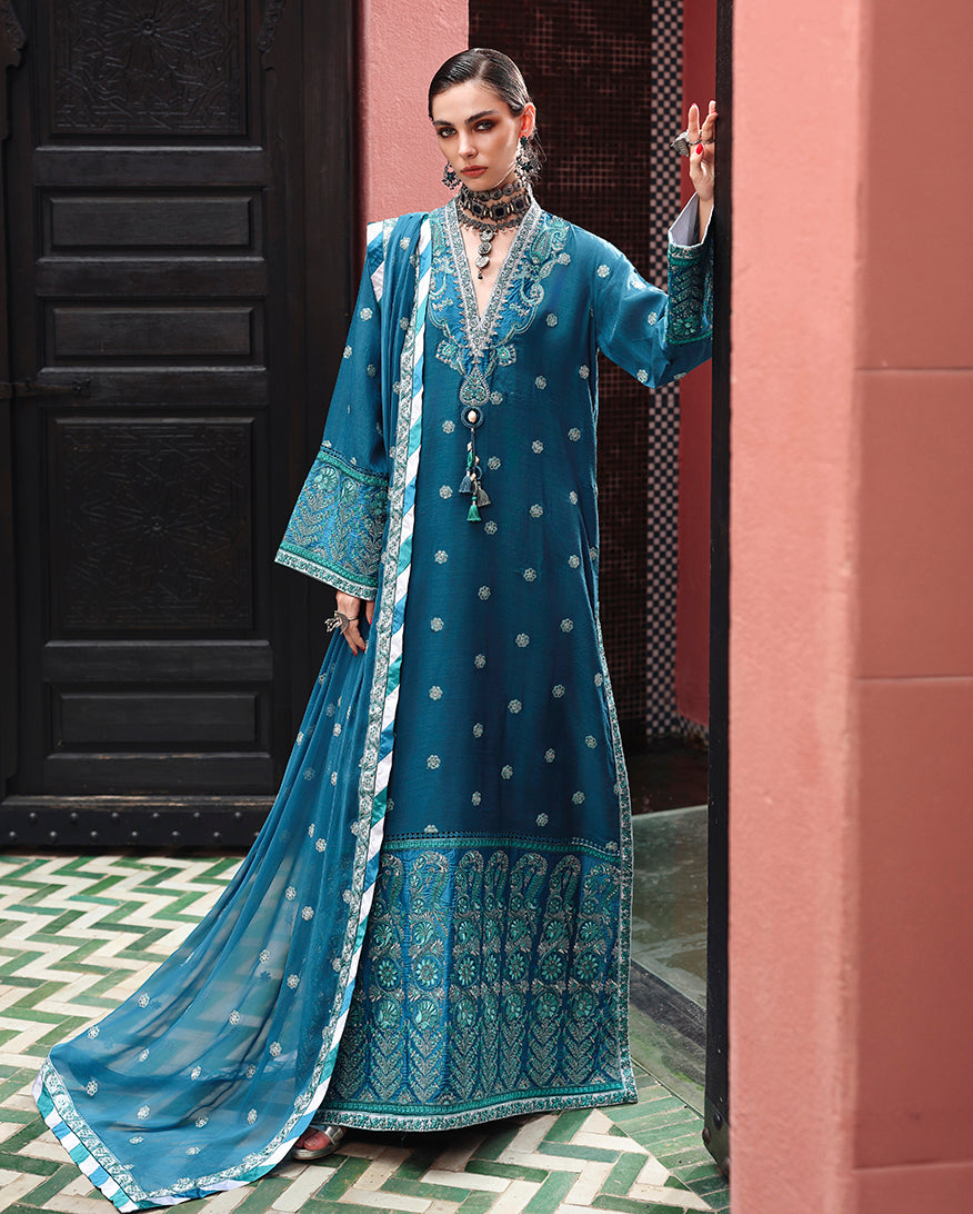 Woman wearing teal embroidered raw silk suit with sequinned border and hand embellished neckline tassels