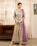 Woman wearing golden beige embellished lama silk suit, front standing by sheer curtains