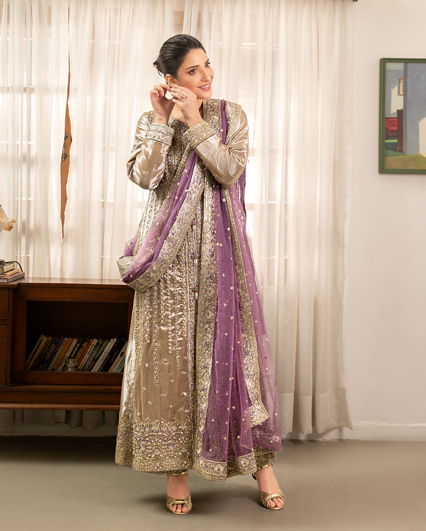 Woman wearing golden beige lama silk suit, front standing, adjusting earring