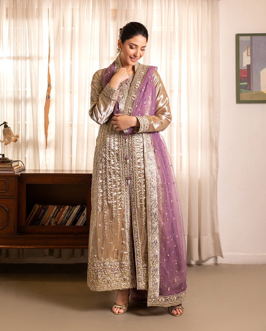 Woman wearing golden beige embellished lama silk suit, front standing, looking down