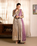 Woman wearing golden beige embellished lama silk suit, front standing, looking down