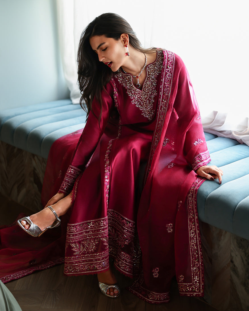 Seated styled shot of magenta pink luxury pret suit with embroidered hem, Zarminay collection