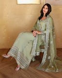 Seated styled shot of sage green luxury pret suit with embroidered hem, Zarminay collection