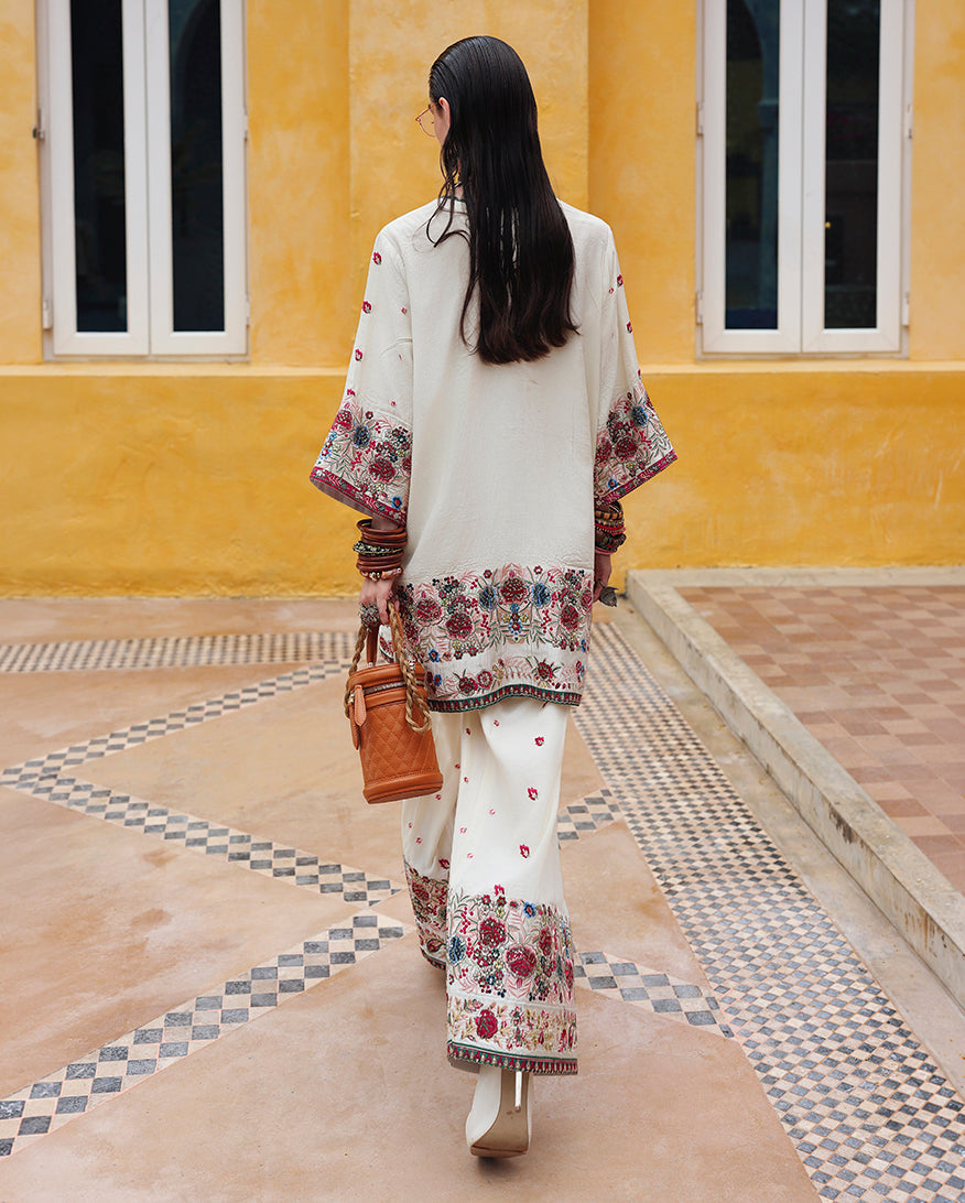 Back view of white raw silk dress showing embroidered sleeve border and dyed silk back