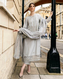 Woman in grey raw silk kurta with resham embroidery and lace-trimmed dupatta, standing by lamp post