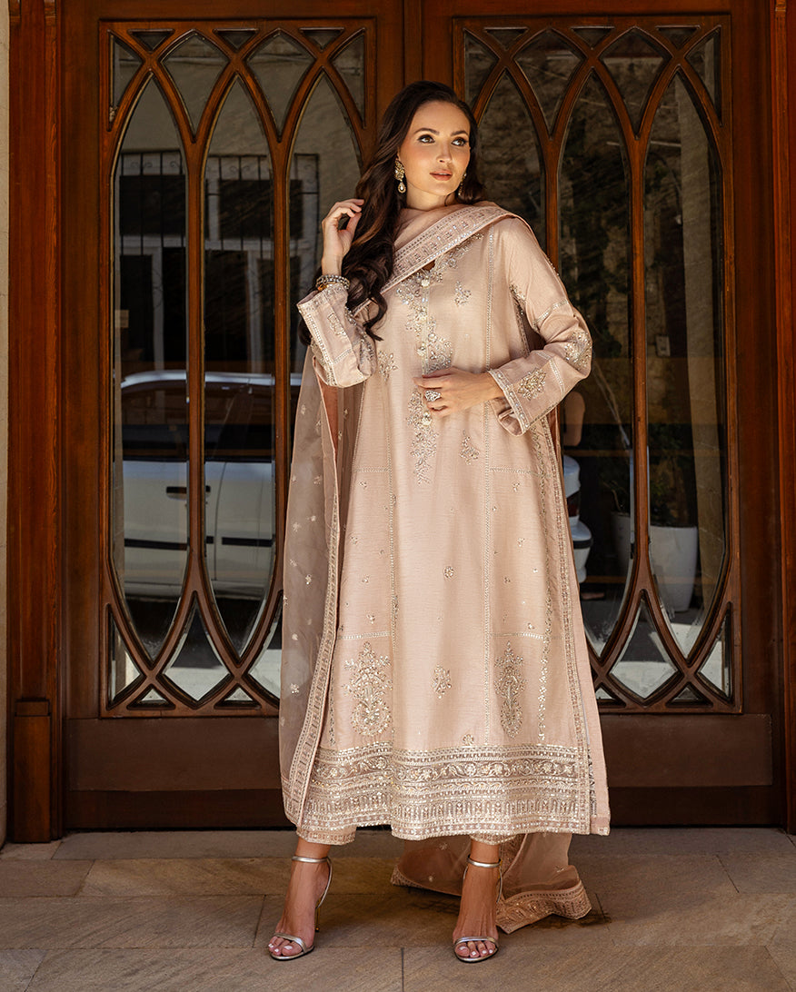 Woman wearing rose beige embroidered raw silk suit looking aside at wooden doorway