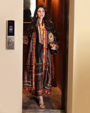 Woman wearing black printed raw silk suit standing in an elevator doorway holding a gold clutch