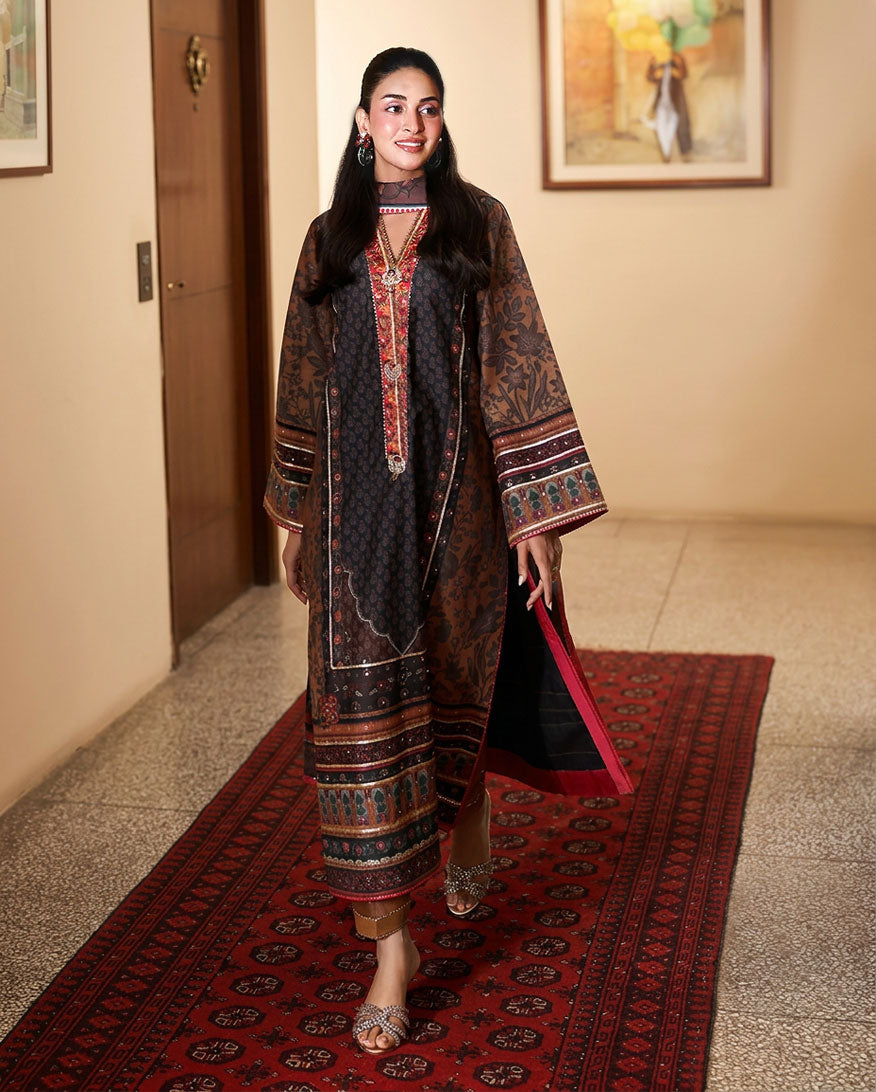 Woman wearing black printed raw silk suit walking down a hallway on a red rug