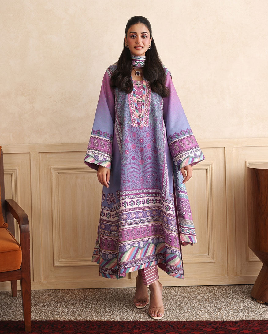 Woman wearing purple printed raw silk suit standing in a wood-panelled room with striped dupatta