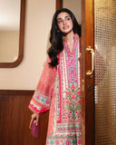 Woman wearing peach printed raw silk suit standing in doorway holding a clutch bag