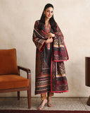 Woman wearing black printed raw silk suit standing beside a chair, holding dupatta