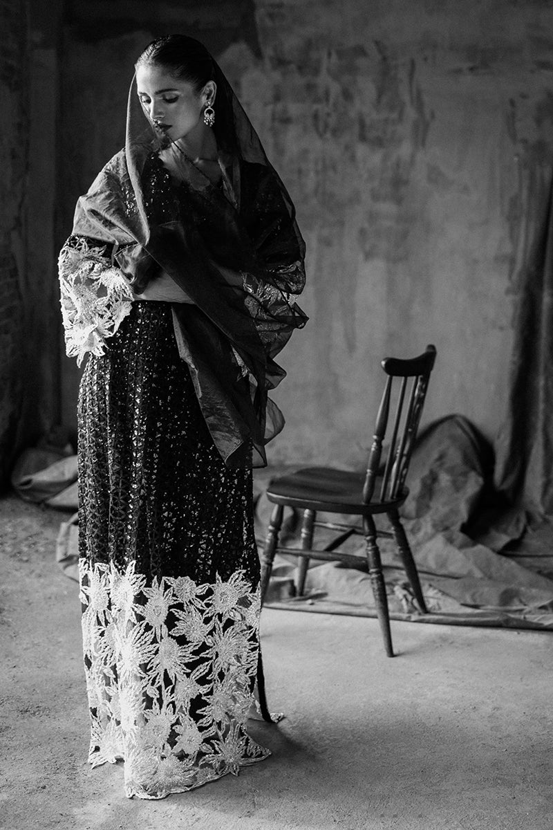 Black-and-white portrait of a Black embroidered Net suit, veiled and looking down